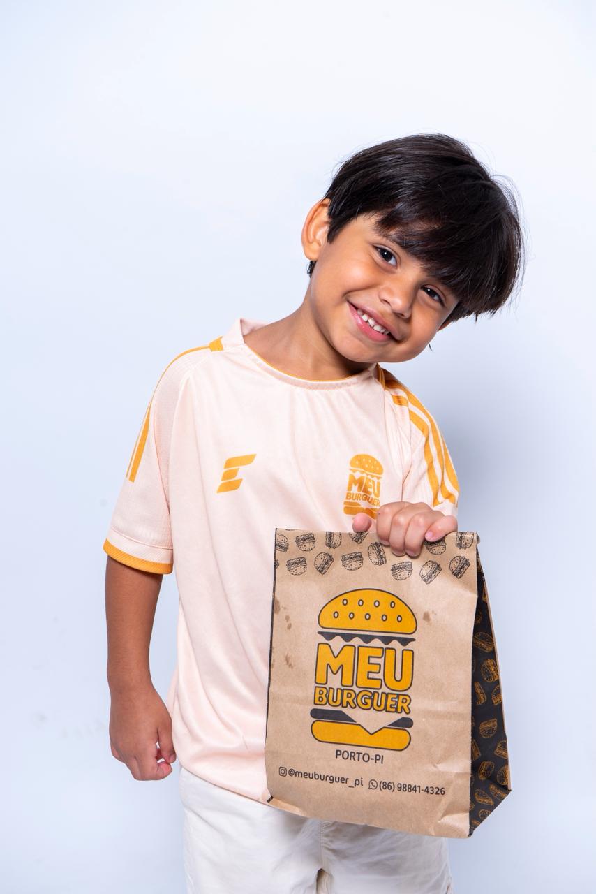 Criança segurando uma sacola do Meu Burguer