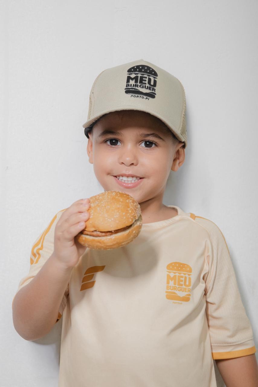 Criança com boné do Meu Burguer segurando um hambúrguer