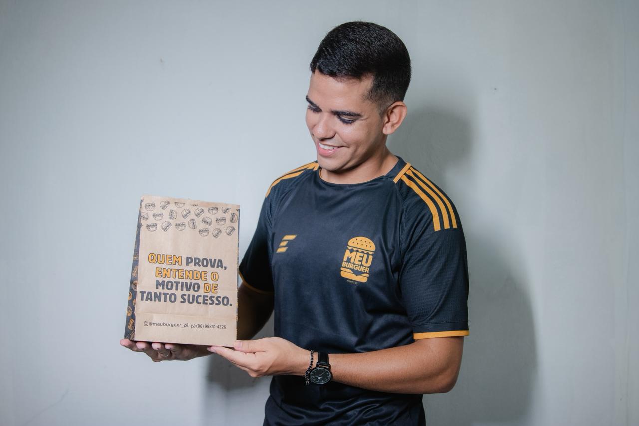 Cliente exibindo a sacola do Meu Burguer